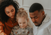 Two parents read a book with their child.