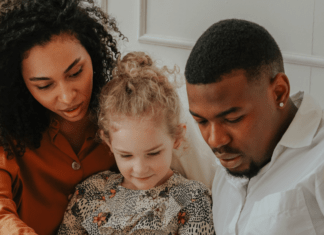 Two parents read a book with their child.