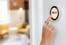 Woman adjusts home thermostat to 76 degrees farenheit