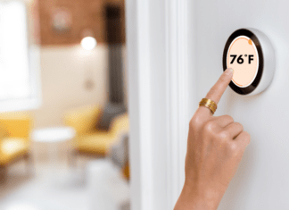Woman adjusts home thermostat to 76 degrees farenheit